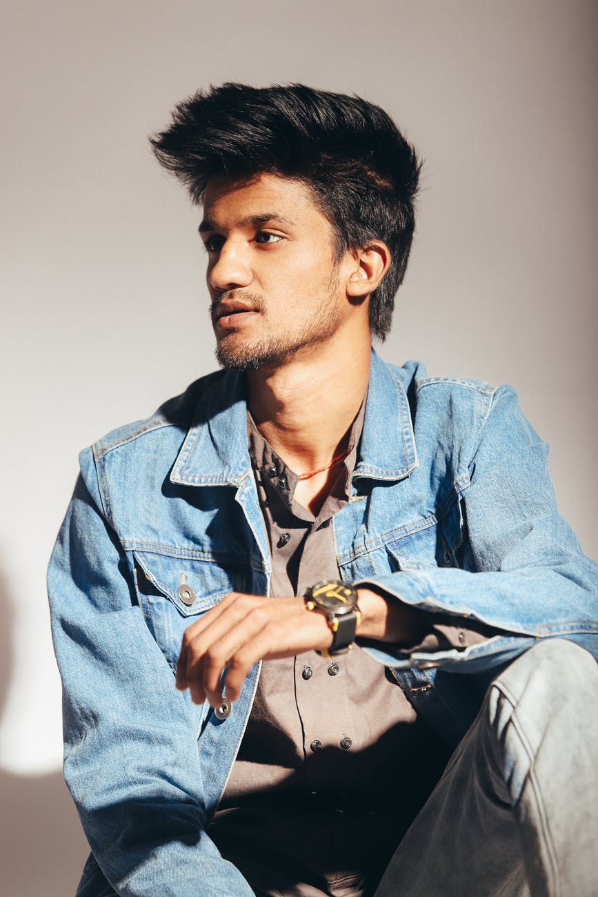 serious ethnic man sitting against white wall