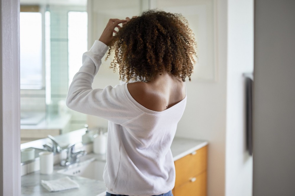 what causes grey hair | rear view of woman looking in the mirror