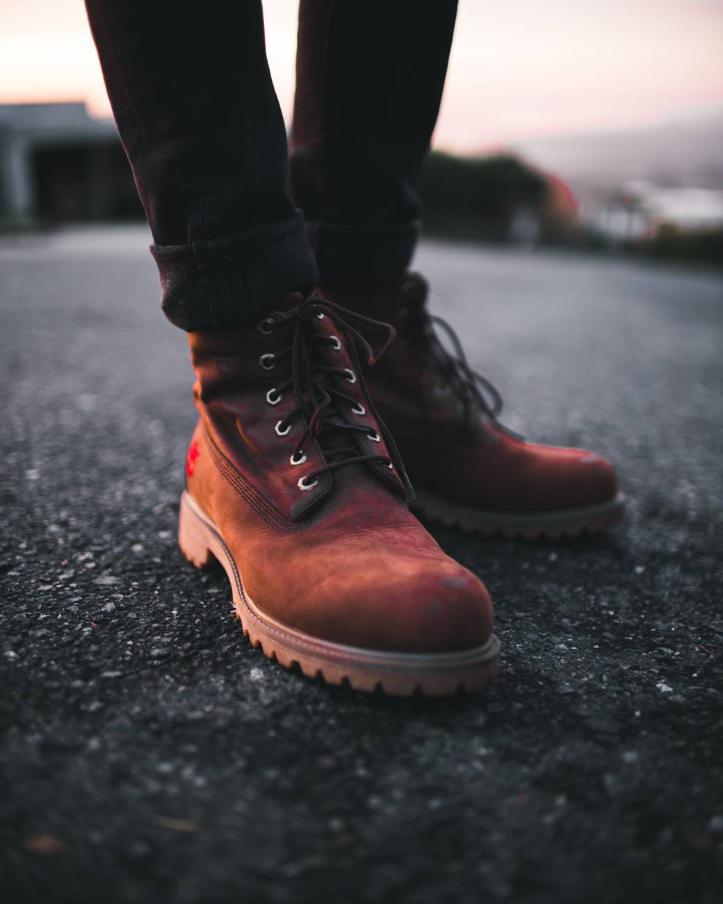 person wearing pair of brown timberland work boots and black denim skinny jeans standing on asphalt road