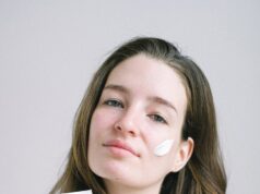 young woman presenting cosmetic product with white swear on face