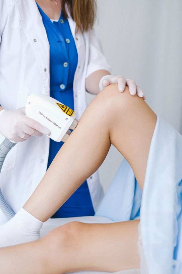 cosmetologist applying low level laser to leg of patient