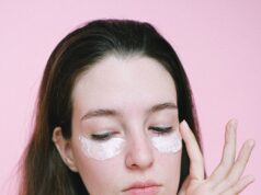 woman applying cosmetic product under eyes