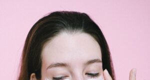 woman applying cosmetic product under eyes