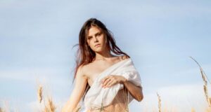young woman standing in field with cloth on breast