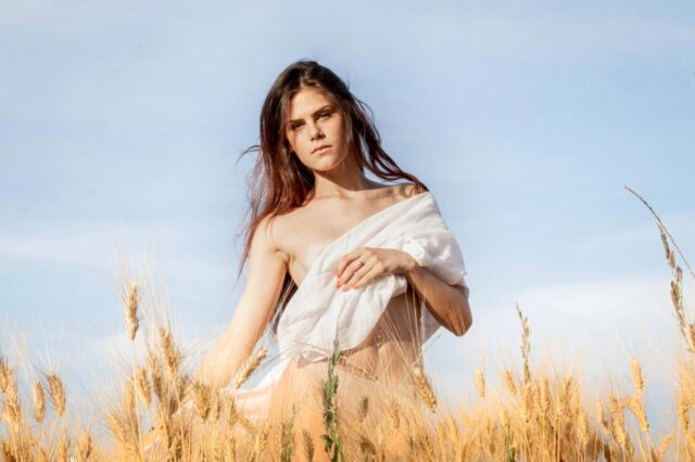 young woman standing in field with cloth on breast