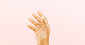 female arm with smear for skin care against pink background