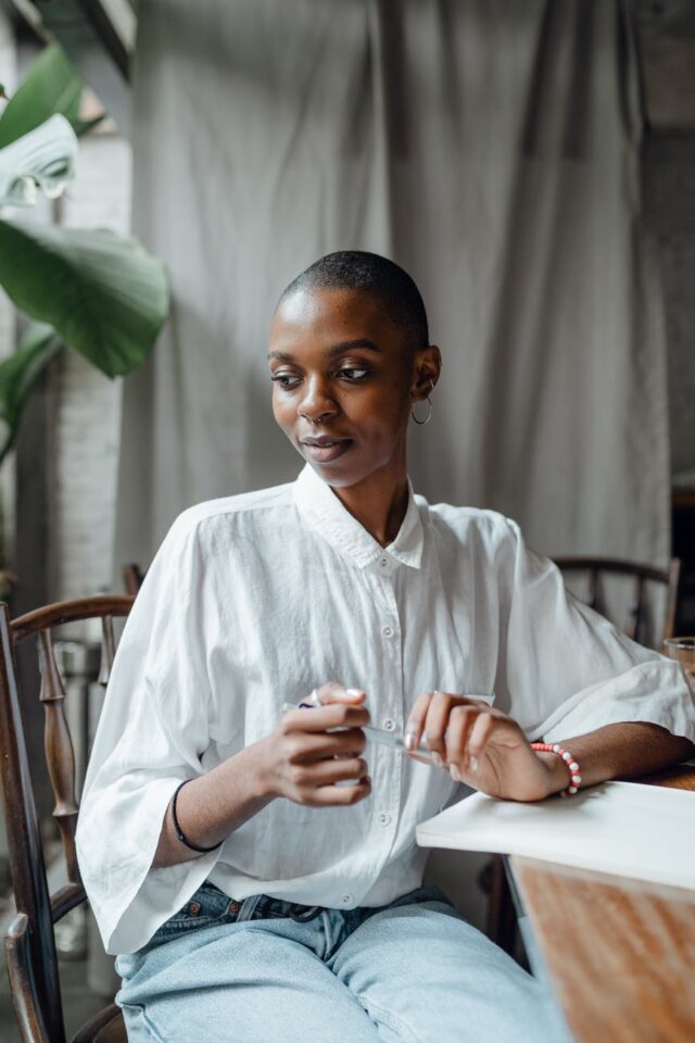 dreamy trendy black woman sitting at table