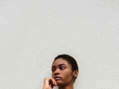 stylish black woman leaning on wall
