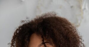 gentle black female with curly hairstyle in bedroom
