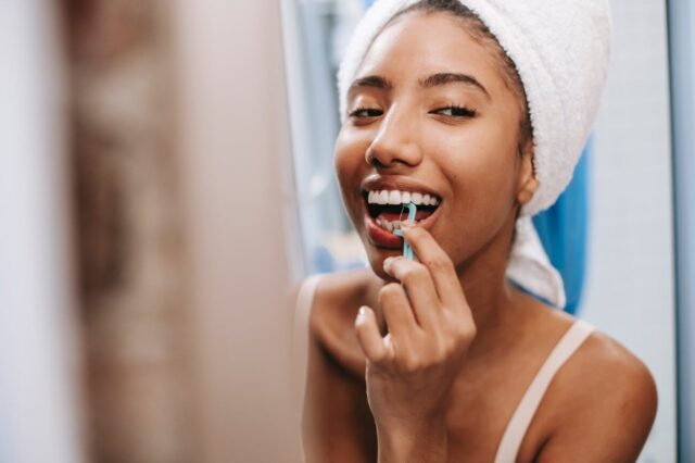 cheerful woman cleaning teeth with flosser